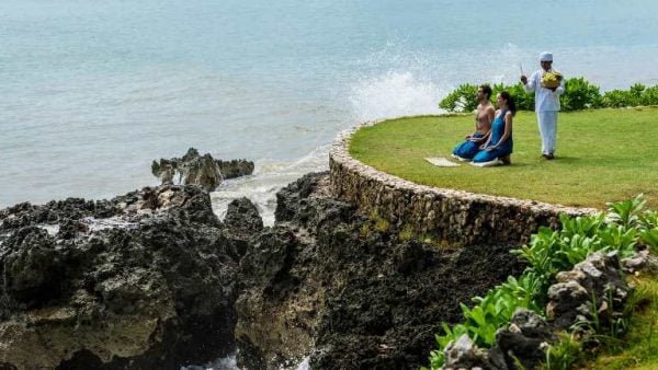 a man and a woman meditating near the shore in Bali