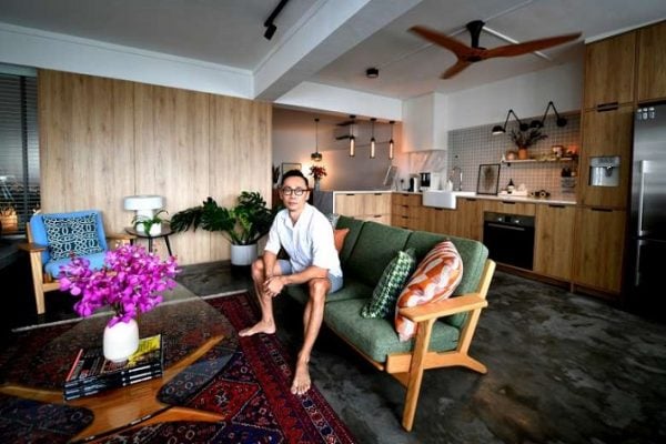 an asian man sitting on his green couch in the living room