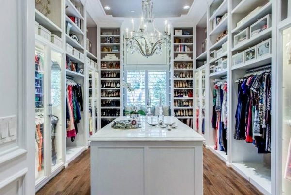 a classic walk-in closet with a chandelier