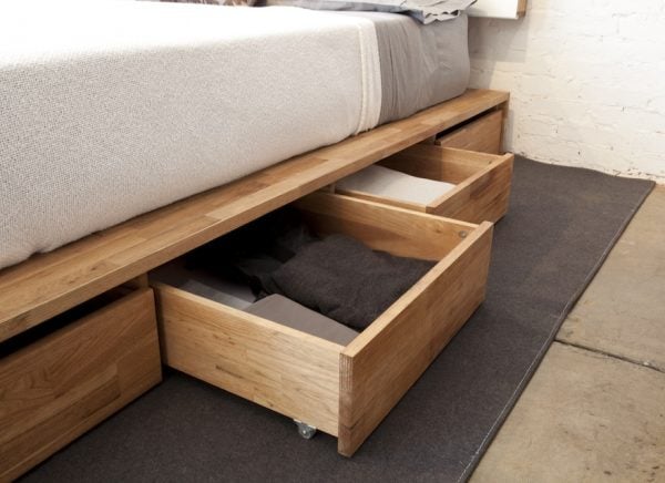 a wooden bedframe installed with drawers stuffed with fitted sheets