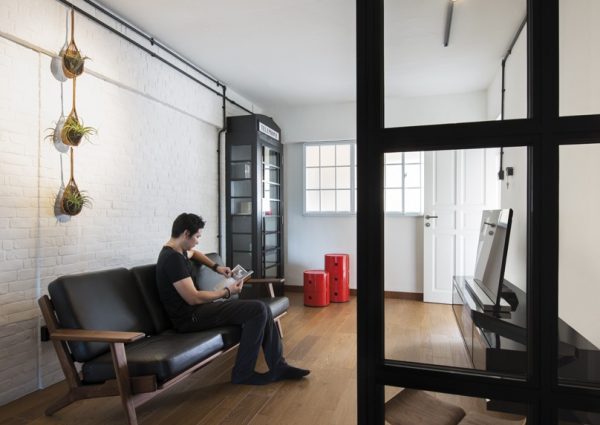 A man sitting on a couch while reading a book in his small apartment